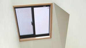 Uma escada com corrimão, uma janela com padrão quadriculado e moldura de madeira.