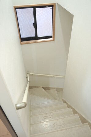 A staircase with a handrail, a window with a grid pattern, and a wooden frame.