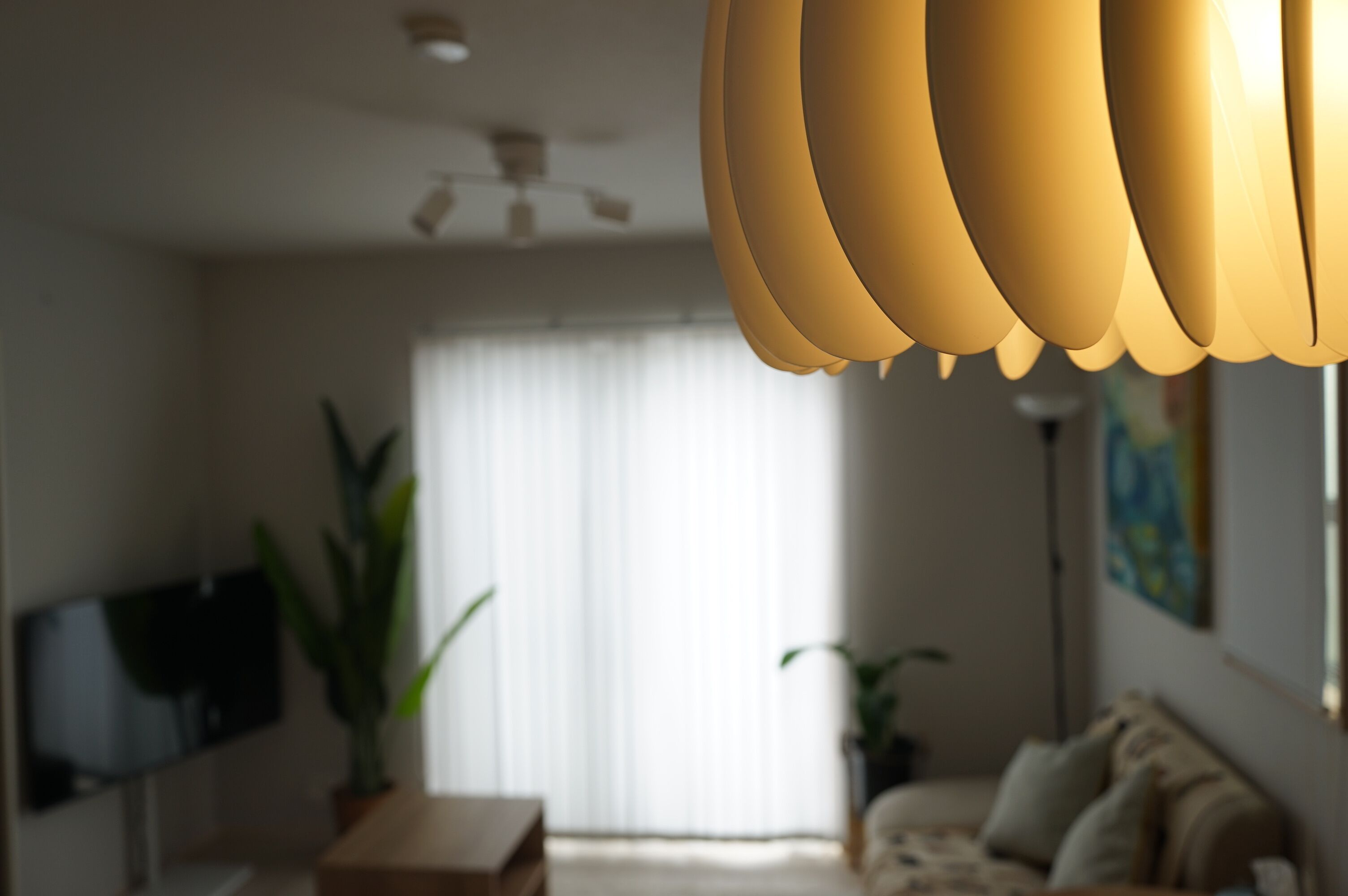 Una sala de estar con televisión de pantalla plana, ventilador de techo, sofá y planta en maceta.