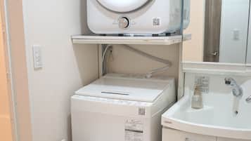 Un espace buanderie compact comprenant un lave-linge, un sèche-linge et un petit évier.