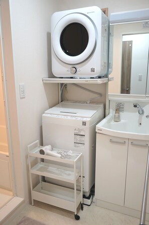 A compact laundry area with a washing machine, a dryer, and a small sink.