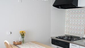Uma cozinha moderna com fogão a gás, exaustor preto e luminária pendente branca.