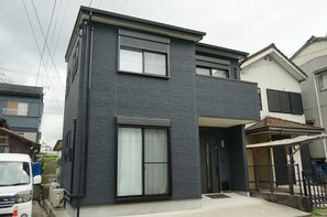 A modern two-story building with a flat roof, large windows, and a visible garage area.