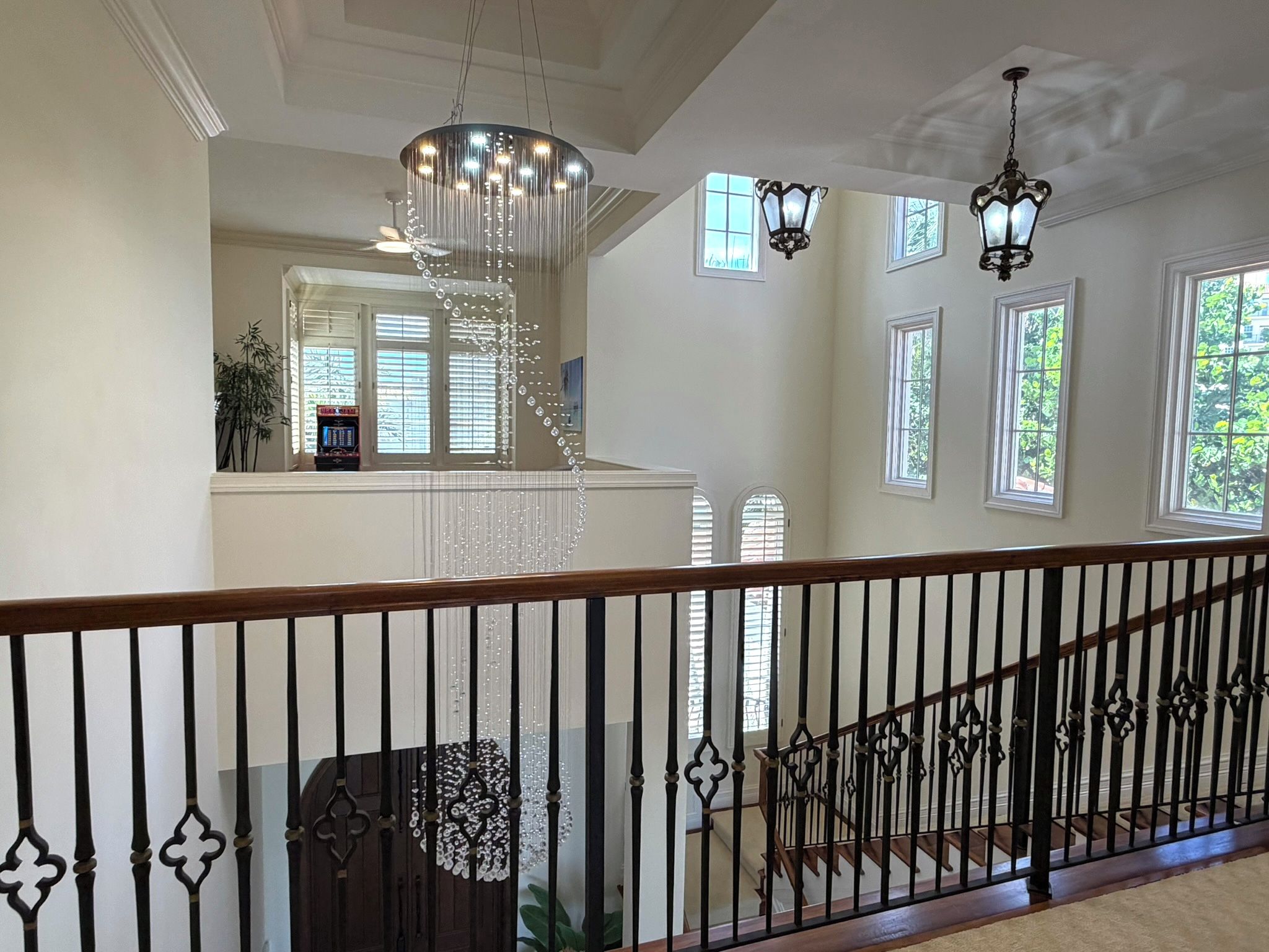 A spacious interior with a grand staircase, a chandelier, and multiple windows allowing natural light.