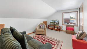 Una sala de estar acogedora con un sofá, un sillón y un tapete rojo estampado.