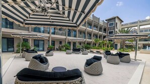Un patio de hotel con mobiliario exterior, sombrillas y una zona de piscina.