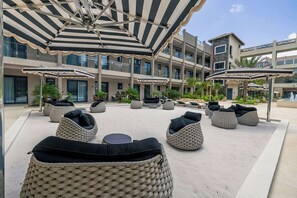 Ein Hotelinnenhof mit Sitzgelegenheiten, Sonnenschirmen und einem Poolbereich.