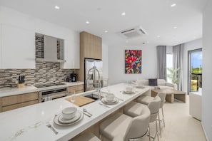 A modern kitchen with a long island, built-in appliances, and a dining area with bar stools. - Brand New Walishali 1BR Condo  Close 2 EagleBeach (Noord)