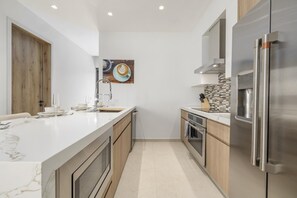 A modern kitchen with a marble countertop, stainless steel appliances, and wooden cabinets. - Brand New Walishali 1BR Condo  Close 2 EagleBeach (Noord)