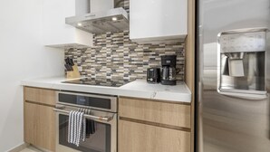 Cocina compacta con horno integrado, cafetera y dispensador de agua en el refrigerador.