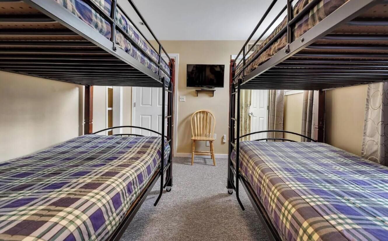 Une chambre avec des lits superposés, une télévision et une chaise.