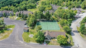 Vue aérienne d’un quartier résidentiel avec des maisons, un court de tennis et une allée.