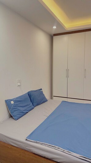 Ein Schlafzimmer mit einem Bett, einem Kleiderschrank und einer Deckenleuchte.