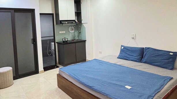 A bedroom with a bed, a built-in wardrobe, a small kitchenette, and a bathroom. - HB Apartment Lang (Hanoi)