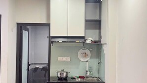 A compact kitchen with a microwave, a small stove, and a sink. - HB Apartment Lang (Hanoi)