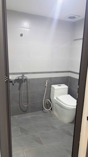 Ein kleines Badezimmer mit Toilette, Dusche und einem Fön.
