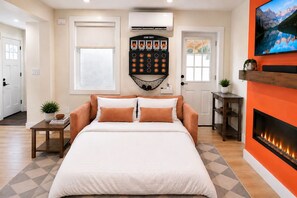 A bedroom with a bed, a wall-mounted game shot machine, a fireplace, and a television. - Studio Near Logan, Hot Tub & Private Entrance (Boston)