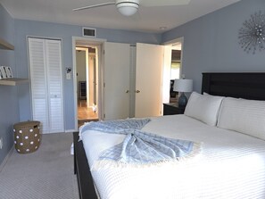 A bedroom with a bed, a nightstand, a lamp, a closet, and a door leading to another room. - Memories Beach Villa! 10 Min to Indian Rocks Beach (Largo)