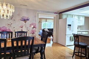 A dining area with a wooden table and chairs, a chandelier, and a wall with floral wallpaper. - Memories Beach Villa! 10 Min to Indian Rocks Beach (Largo)