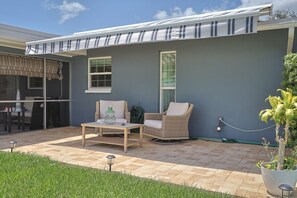A patio with a table and chairs, a potted plant, and a hose on the ground. - Memories Beach Villa! 10 Min to Indian Rocks Beach (Largo)