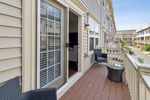 A balcony with wicker furniture, a glass table, and a view of neighboring buildings. - Your Oasis Away From Home, 4-bedroom townhome in Greenbelt (Greenbelt)