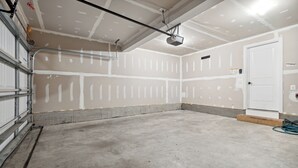 Ett garage med oputsade väggar, ett betonggolv och en dörr.