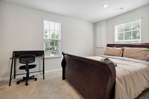 A bedroom with a bed, a desk with a chair, and two windows with blinds. - Your Oasis Away From Home, 4-bedroom townhome in Greenbelt (Greenbelt)