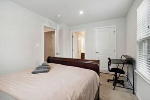 A bedroom with a bed, a desk, and a chair. There are two doors, one leading to a bathroom and another to a closet. - Your Oasis Away From Home, 4-bedroom townhome in Greenbelt (Greenbelt)