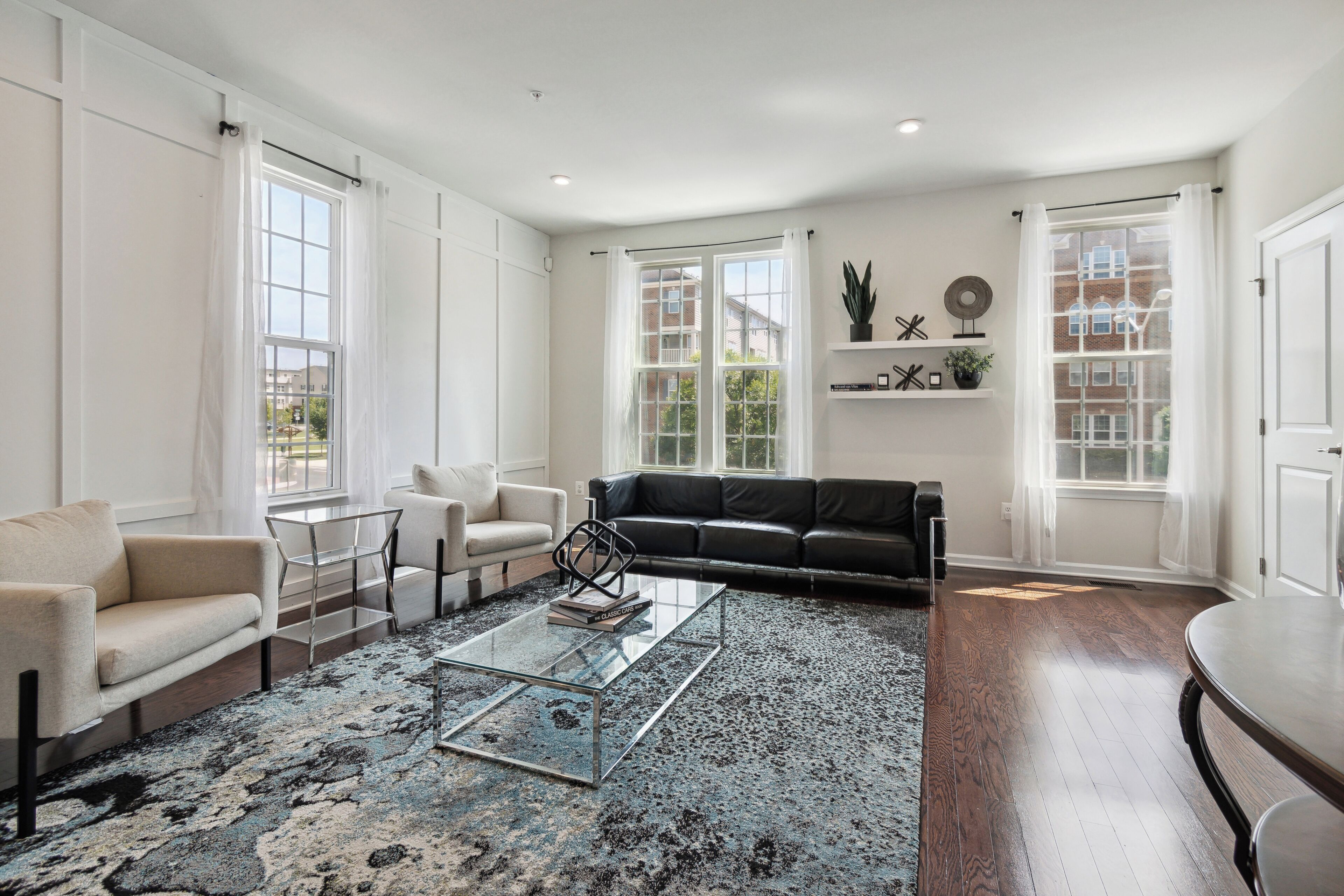 A spacious living room with a sofa, armchairs, a coffee table, and a bookshelf.