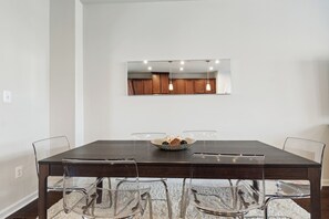 A dining area with a rectangular table, four chairs, a mirror above the table, and a bowl with decorative items on the table. - Your Oasis Away From Home, 4-bedroom townhome in Greenbelt (Greenbelt)
