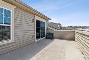 A residential balcony with a sliding glass door, a small trash bin, and a clear view of the neighborhood. - Your Oasis Away From Home, 4-bedroom townhome in Greenbelt (Greenbelt)