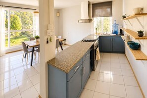A modern kitchen with a central island, a dining area with a view, and a large window. - 3BR Sunset Sea View, Steps to Flic en Flac Beach (Flic en Flac)