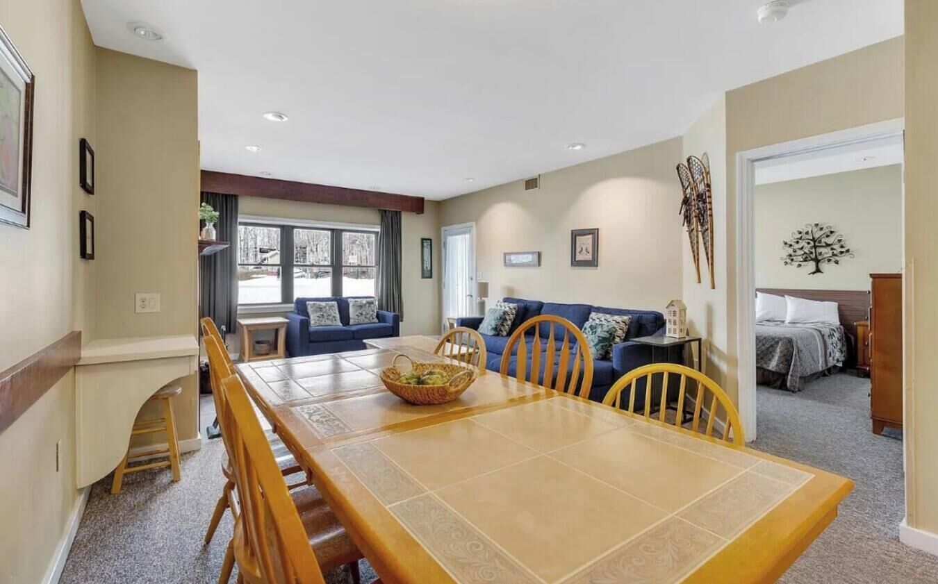 A dining area with a wooden table and chairs, a blue sofa, and a small side table with a basket.