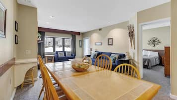 A dining area with a wooden table and chairs, a blue sofa, and a small side table with a basket.