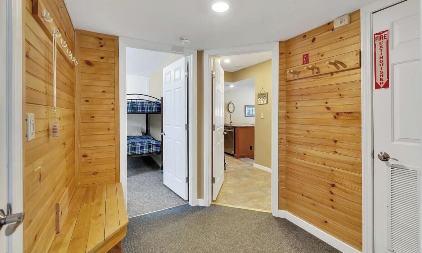 Een gang met houten lambrisering, een stapelbed en een deur met een bord 'vluchtweg'.