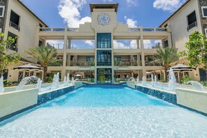 A hotel with a central pool, multiple balconies, and a distinctive architectural design. - Brand New Top Floor 2BR2BA Condo near Eagle Beach (Oranjestad)
