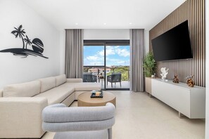 Un salon moderne avec un canapé, une table basse ronde et un téléviseur à écran plat fixé sur un mur recouvert de panneaux en bois.