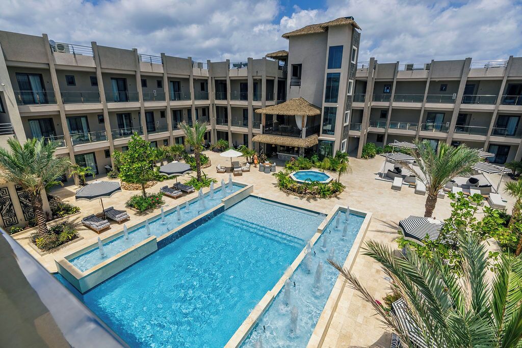 Un hôtel doté d’une grande piscine extérieure, de nombreux balcons et d’espaces de détente agrémentés de parasols.