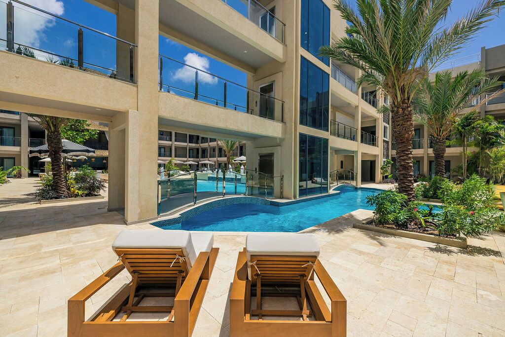 Un hotel con piscina, lettini e palme.