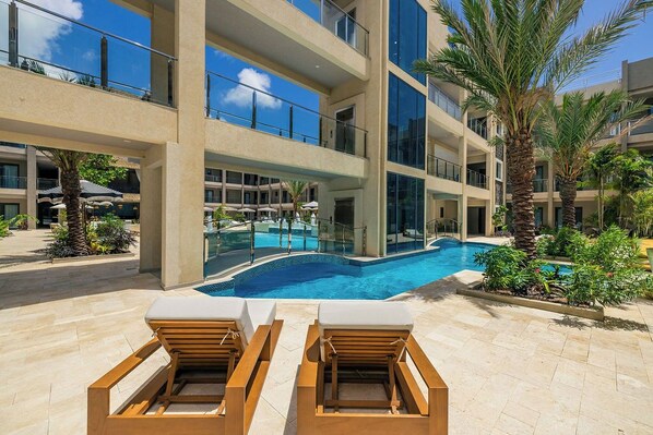 Un hôtel doté d’une piscine, de chaises longues et de palmiers.