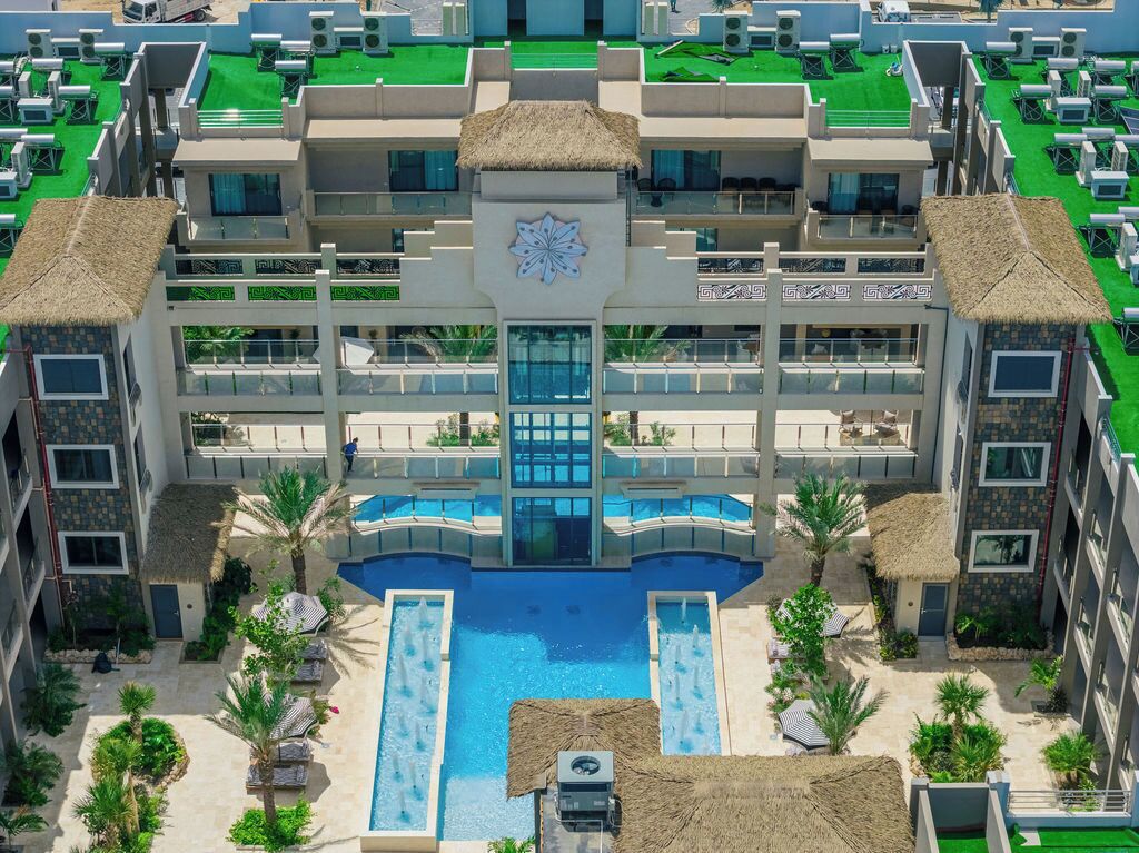 Un hotel a più piani con piscina centrale, area salotto all'aperto e un design architettonico particolare.