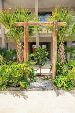 Un jardin agrémenté d’une pergola en bois, de différentes plantes et d’un petit arbre.