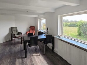 Ein stilvolles Esszimmer mit einem großen Tisch, zwei Stühlen und einem Fenster mit Blick ins Grüne.