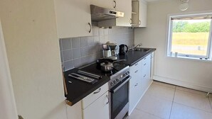A kitchen with a stove, oven, and a window with a view of greenery. - 2 Person Holiday Home in Vra (Vra)