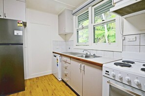 Una cocina compacta equipada con refrigerador, lavavajillas, pileta y estufa.