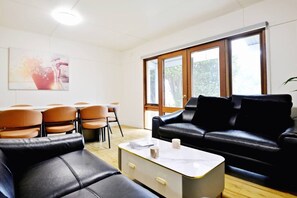 Una sala de estar moderna con un sofá de cuero negro, una mesa de centro y un comedor con sillas.