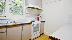 Una cucina con piano cottura, forno e lavello. Una finestra offre vista su del verde circostante.