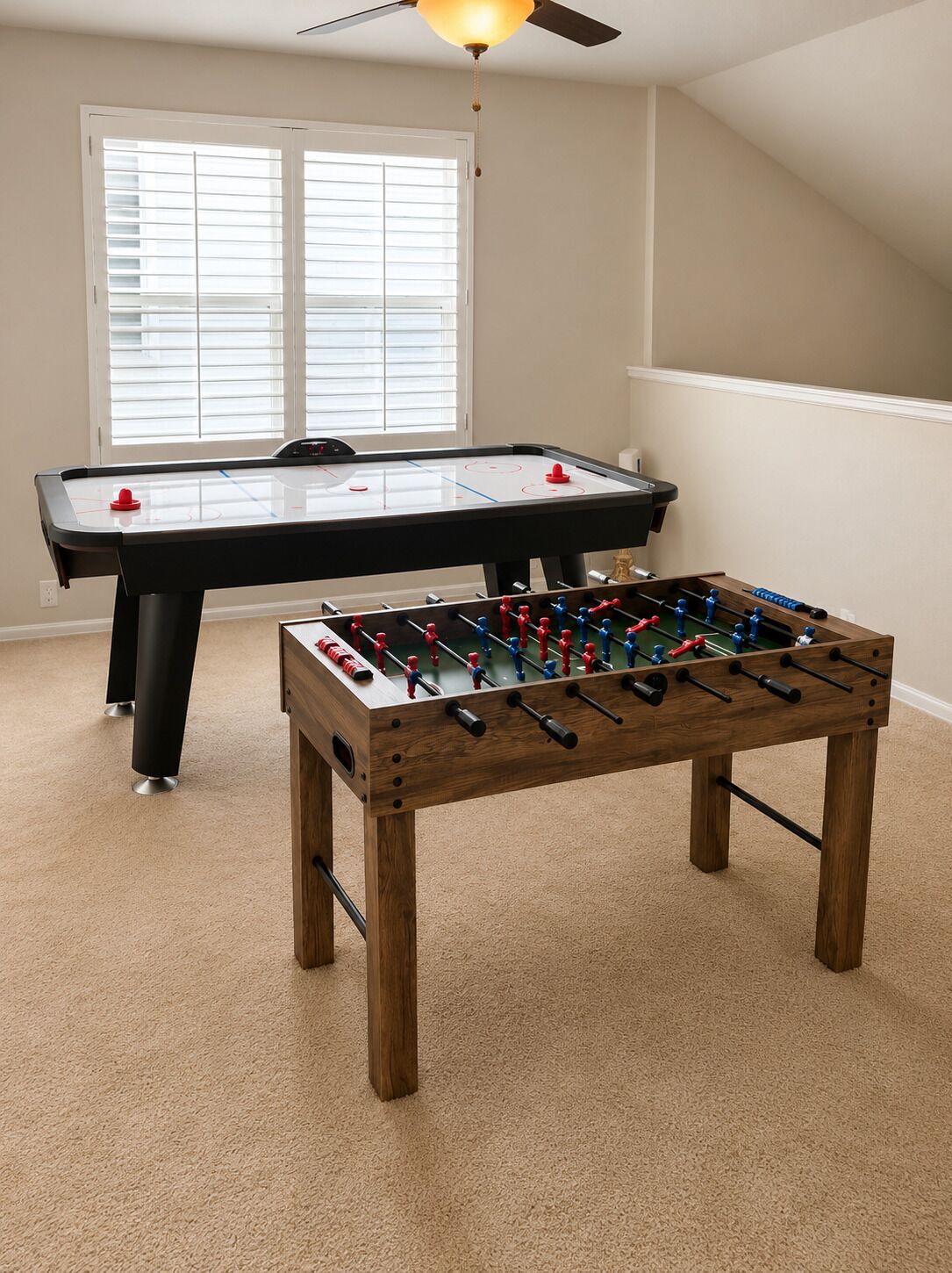 Um quarto com mesa de futebol e mesa de pingue-pongue.