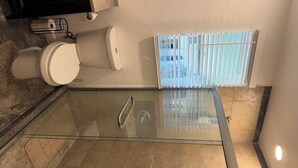Eine Badewanne mit Glasumrandung, ein Duschbereich, eine Toilette und ein Handtuchhalter.