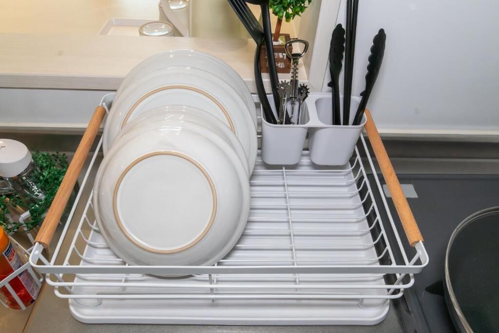 A white dish rack with plates and utensils.